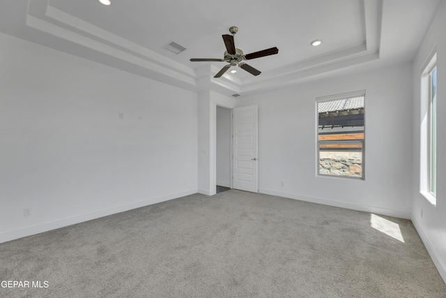 carpeted empty room with a ceiling fan, a healthy amount of sunlight, a tray ceiling, and recessed lighting