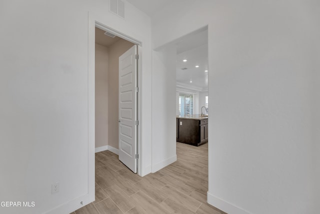 corridor featuring visible vents, baseboards, recessed lighting, and light wood finished floors