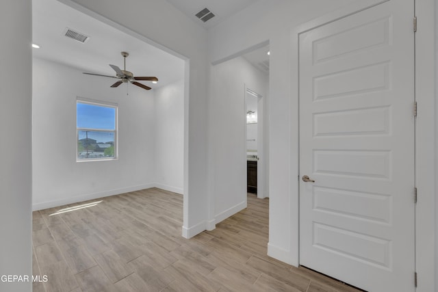spare room with light wood finished floors, baseboards, a ceiling fan, and visible vents