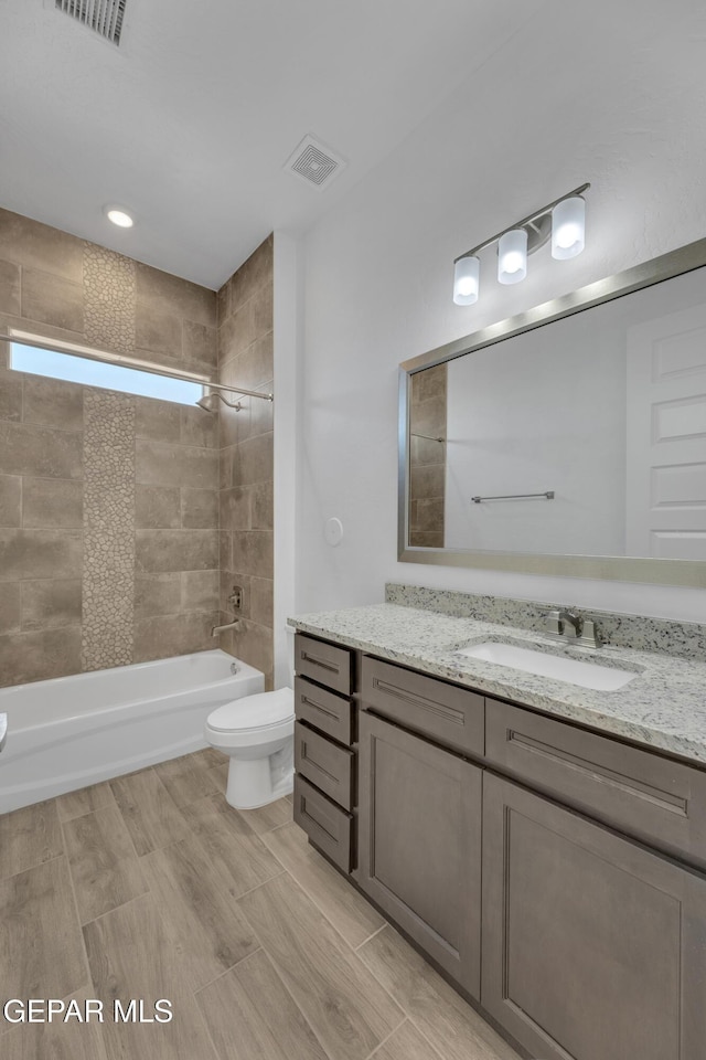full bathroom with visible vents, vanity, shower / tub combination, and toilet