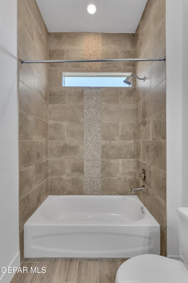 bathroom featuring plenty of natural light, toilet, wood finished floors, and  shower combination