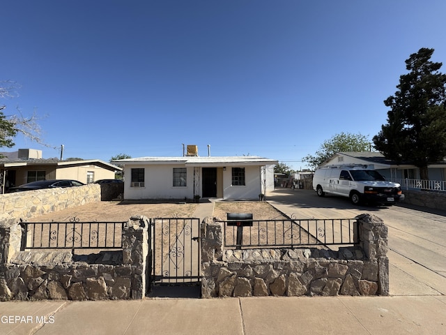 bungalow-style house with a gate, concrete driveway, and a fenced front yard