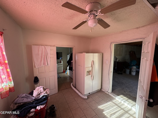 bedroom featuring a ceiling fan, light tile patterned flooring, a textured ceiling, and white refrigerator with ice dispenser