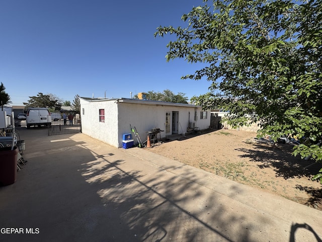 rear view of property with stucco siding, fence, a gate, and concrete driveway