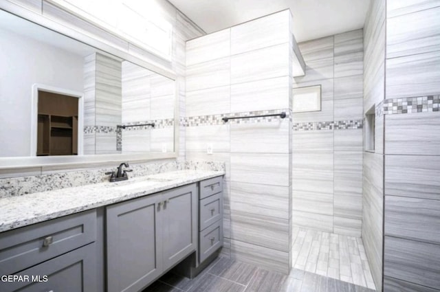 bathroom with a tile shower, tile patterned flooring, and vanity