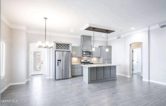 kitchen featuring appliances with stainless steel finishes, light countertops, gray cabinets, arched walkways, and backsplash