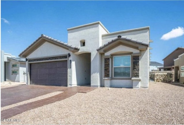 view of front of property featuring a garage, stucco siding, a tile roof, and driveway