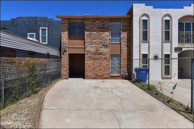 view of front of property featuring brick siding, stucco siding, and fence