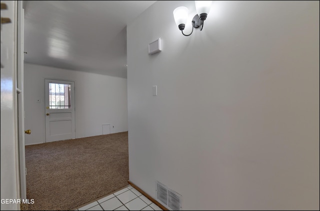 corridor with light tile patterned floors, visible vents, and light carpet