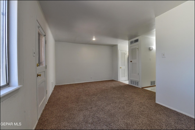 unfurnished room featuring baseboards, visible vents, and carpet flooring