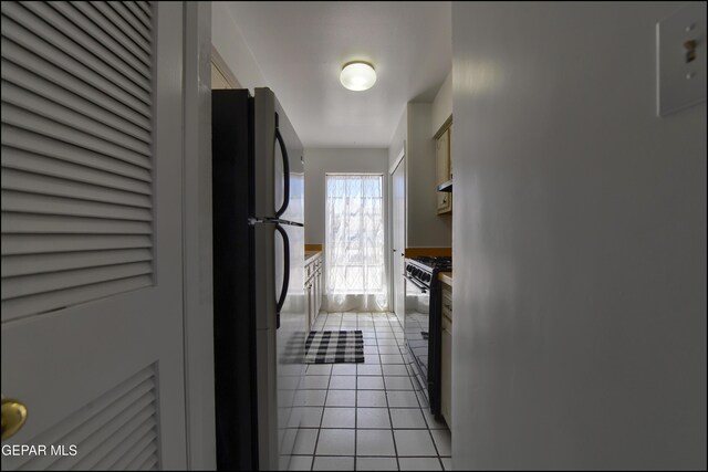 kitchen featuring under cabinet range hood, black appliances, and light tile patterned flooring