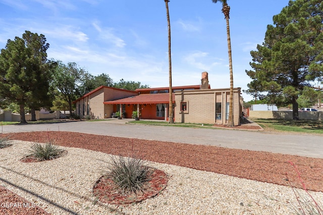 5673 Upper Valley Rd, El Paso, TX 79932 - mid-century home featuring a chimney, brick siding, and curved driveway