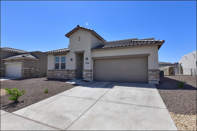13162 Cleethorpes St, El Paso, TX 79928 - mediterranean / spanish home featuring a garage, driveway, stone siding, a tiled roof, and stucco siding
