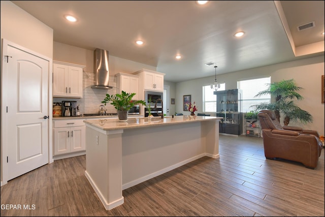 13162 Cleethorpes St, El Paso, TX 79928 - kitchen with wall chimney range hood, white cabinets, visible vents, open floor plan, and dark wood-type flooring
