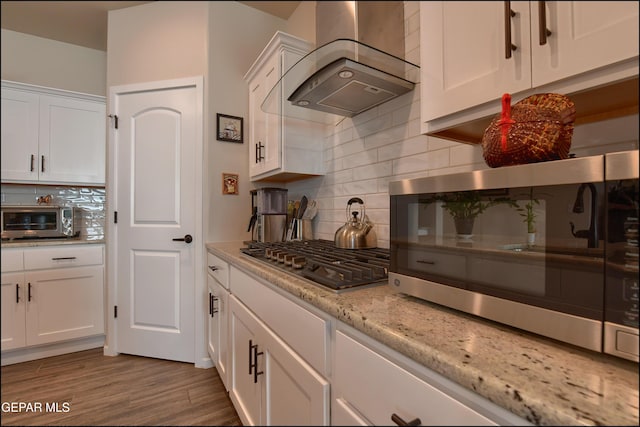 13162 Cleethorpes St, El Paso, TX 79928 - kitchen featuring backsplash, white cabinets, appliances with stainless steel finishes, and wall chimney range hood