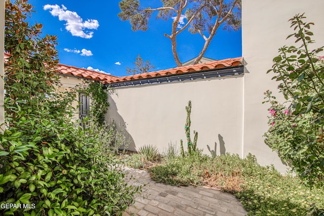 view of side of home with stucco siding and a tile roof