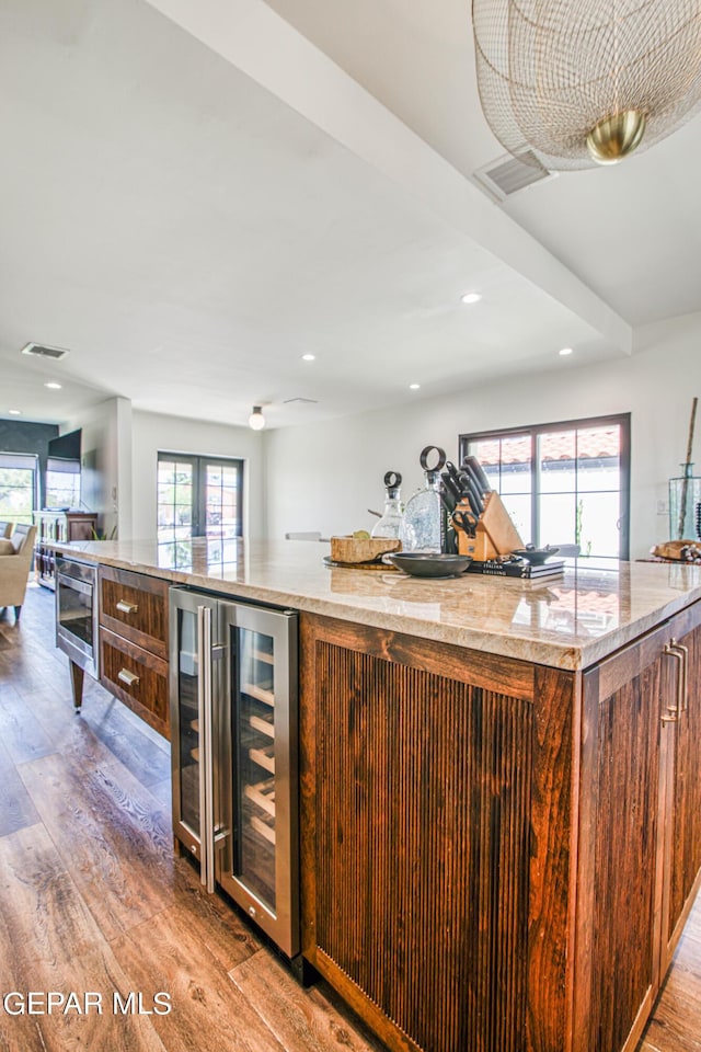 kitchen featuring visible vents, open floor plan, a large island, light wood finished floors, and wine cooler