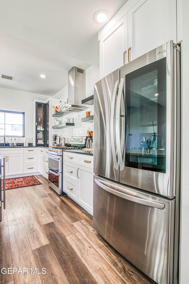 kitchen featuring open shelves, island range hood, visible vents, stainless steel appliances, and dark countertops