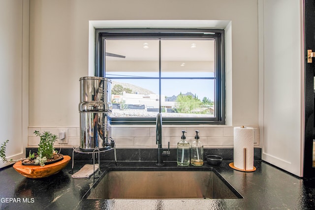 interior space with dark stone counters, backsplash, and a sink