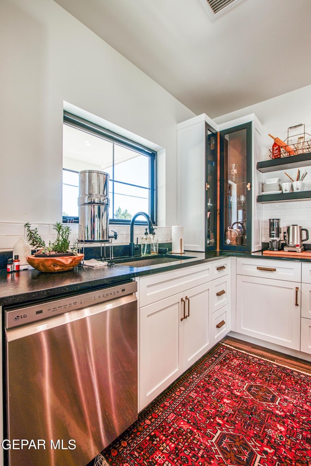 kitchen featuring white cabinets, backsplash, dark countertops, dishwasher, and a sink