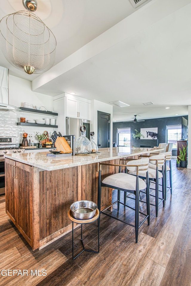 kitchen with light stone countertops, a wealth of natural light, stainless steel appliances, and dark wood finished floors