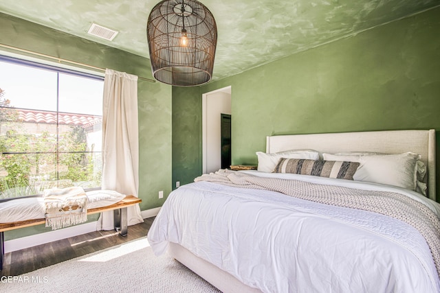 bedroom with baseboards, visible vents, and wood finished floors