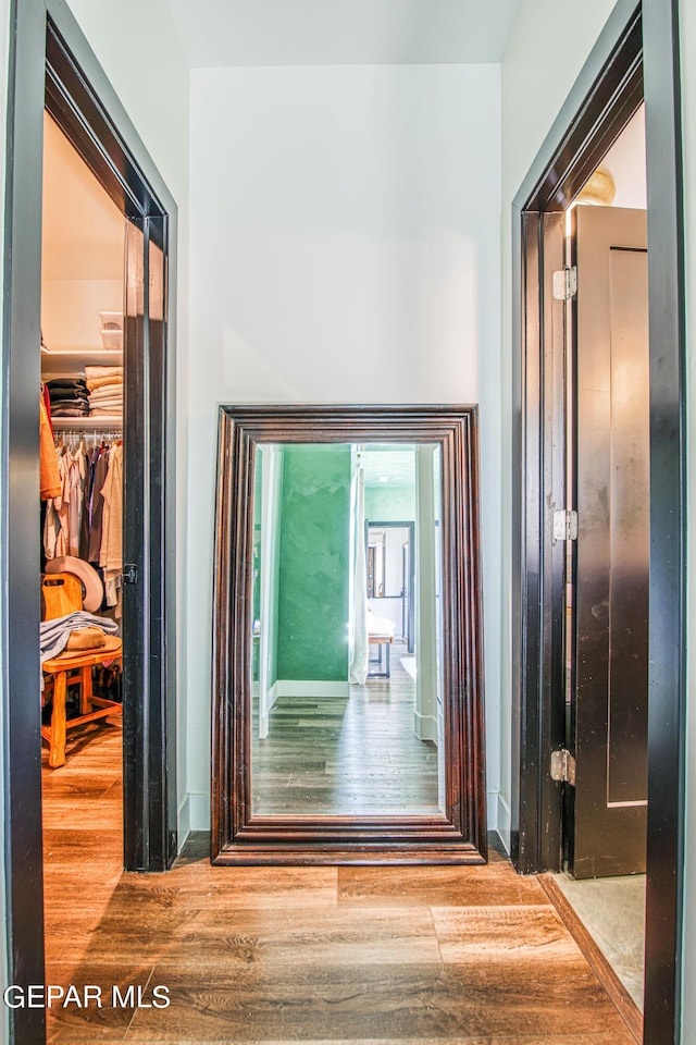 corridor featuring baseboards and wood finished floors