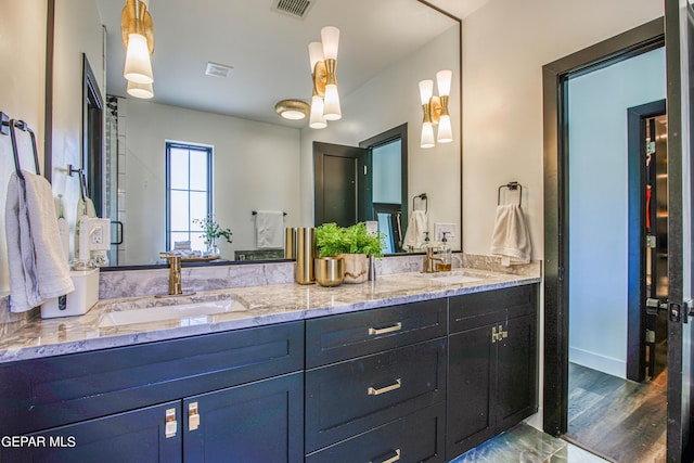 full bath with visible vents, wood finished floors, double vanity, and a sink