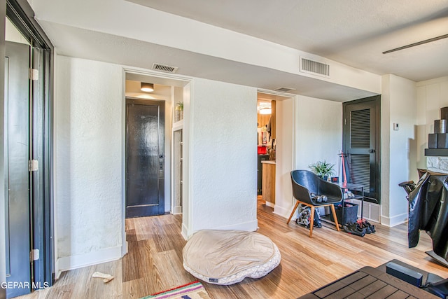 living room featuring baseboards, visible vents, wood finished floors, and a textured wall