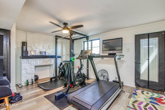 workout area featuring a fireplace, a ceiling fan, wood finished floors, and baseboards