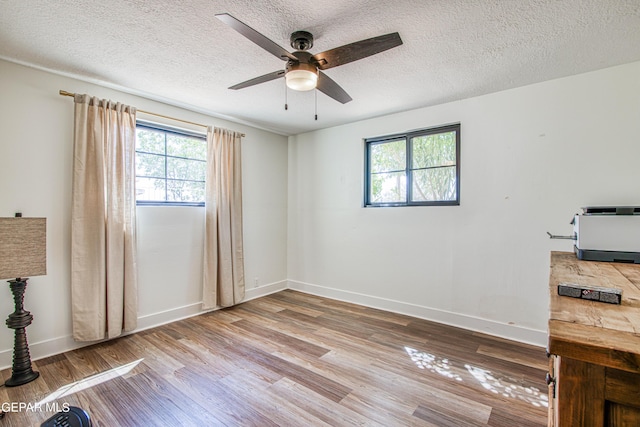 unfurnished room featuring a ceiling fan, a textured ceiling, wood finished floors, and baseboards