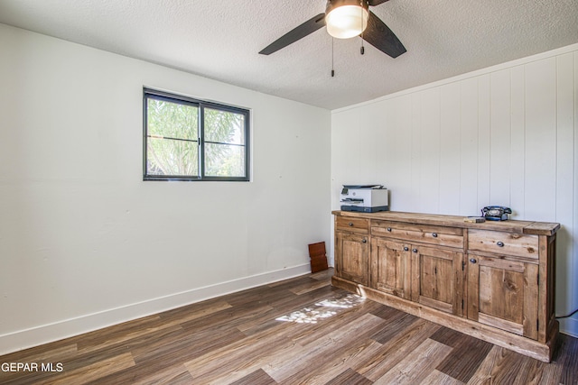 office featuring a textured ceiling, ceiling fan, baseboards, and dark wood finished floors