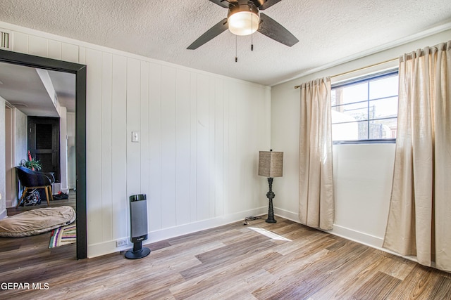 spare room with baseboards, ceiling fan, a textured ceiling, and light wood finished floors