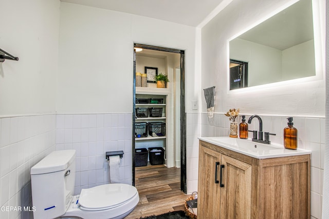 bathroom featuring tile walls, a wainscoted wall, toilet, and vanity