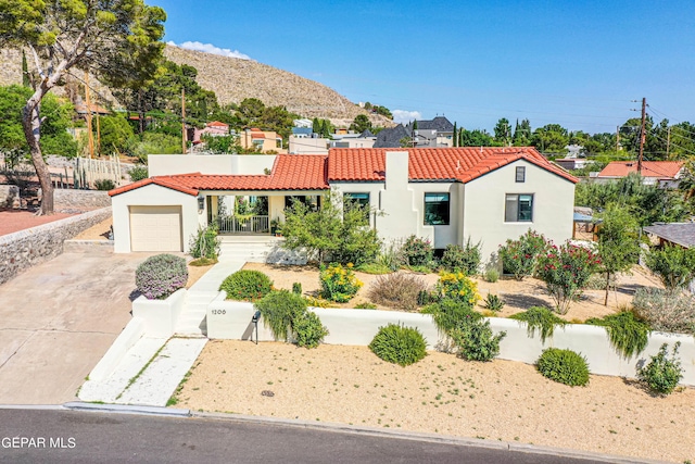 mediterranean / spanish-style house featuring driveway, fence, a tile roof, an attached garage, and stucco siding