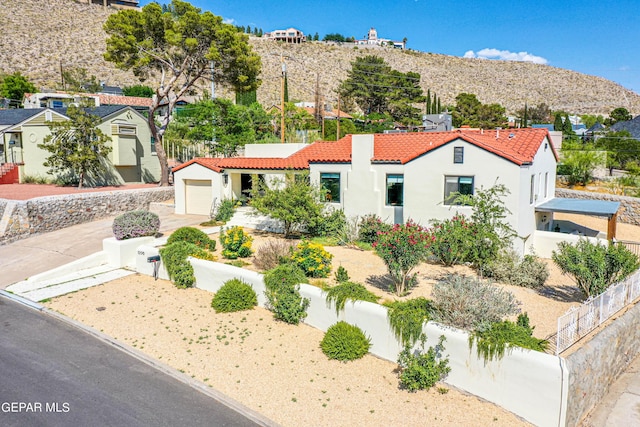 mediterranean / spanish-style home with fence, stucco siding, a tiled roof, and a residential view