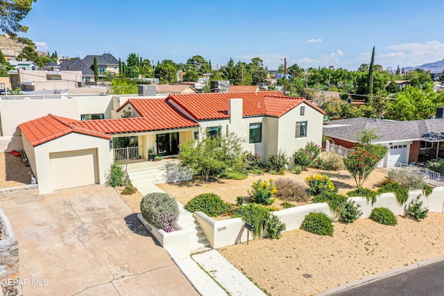 mediterranean / spanish-style house featuring a tile roof, a garage, driveway, stucco siding, and fence