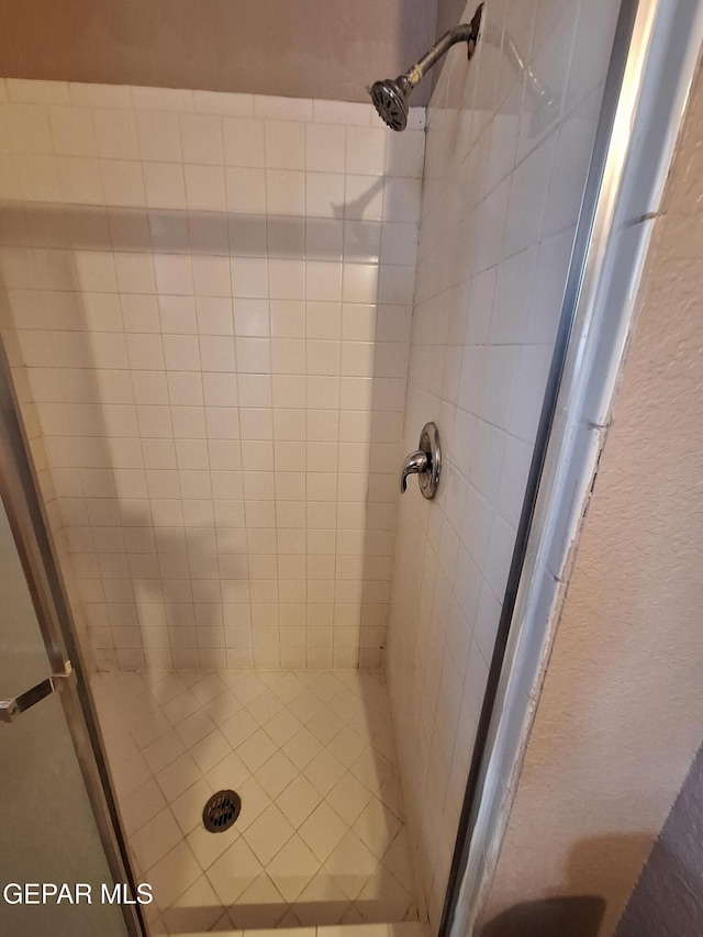 full bathroom with a textured wall and a shower stall