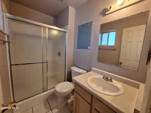 bathroom featuring vanity, toilet, a stall shower, a textured wall, and tile patterned flooring