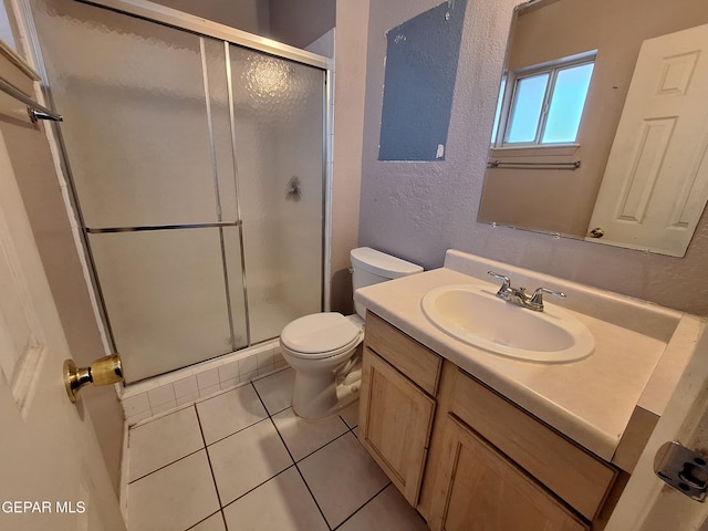 bathroom with tile patterned floors, a stall shower, toilet, and a textured wall