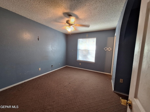 empty room featuring dark colored carpet, a textured ceiling, ceiling fan, and baseboards
