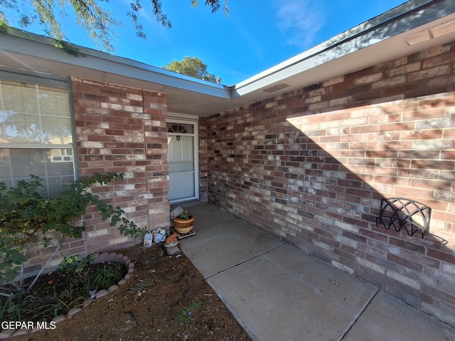 view of exterior entry featuring brick siding