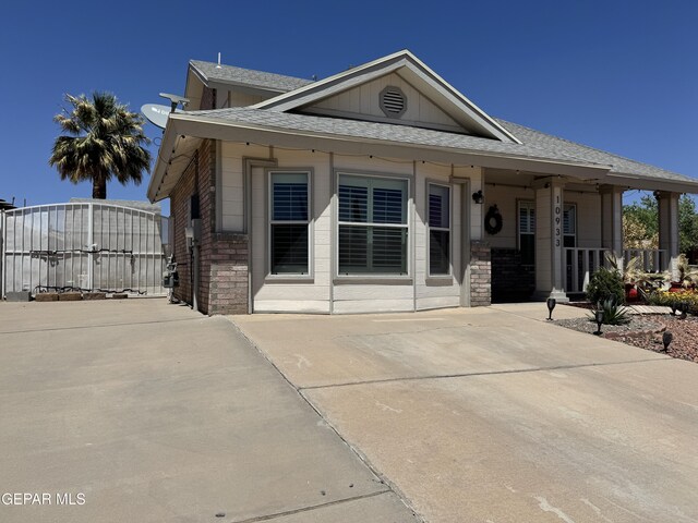 10933 Chippendale Ave, El Paso, TX 79934 - view of front of house with a shingled roof, a gate, covered porch, and board and batten siding