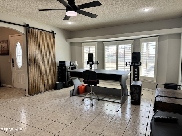 10933 Chippendale Ave, El Paso, TX 79934 - interior space featuring a ceiling fan, a barn door, a textured ceiling, arched walkways, and light tile patterned floors
