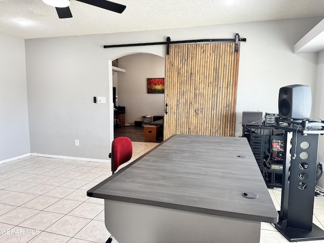 10933 Chippendale Ave, El Paso, TX 79934 - home office featuring arched walkways, ceiling fan, light tile patterned floors, and a barn door