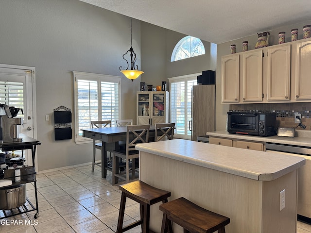 kitchen featuring a center island, hanging light fixtures, stainless steel dishwasher, light countertops, and a toaster