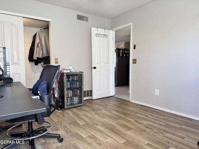 office space featuring visible vents, a textured ceiling, and light wood-style floors