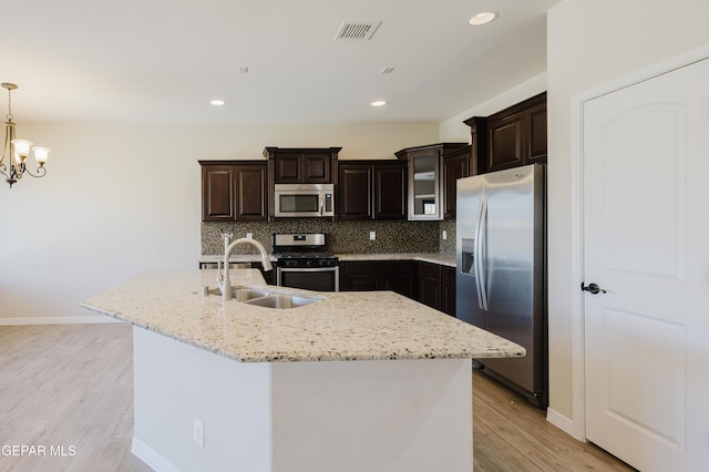 13145 Hazy, El Paso, TX 79938 - kitchen featuring appliances with stainless steel finishes, decorative backsplash, light wood finished floors, dark brown cabinets, and pendant lighting