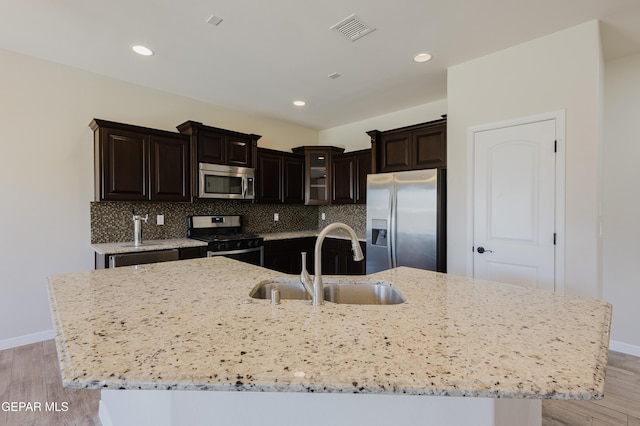 13145 Hazy, El Paso, TX 79938 - kitchen featuring stainless steel appliances, light wood finished floors, a large island with sink, light stone countertops, and recessed lighting