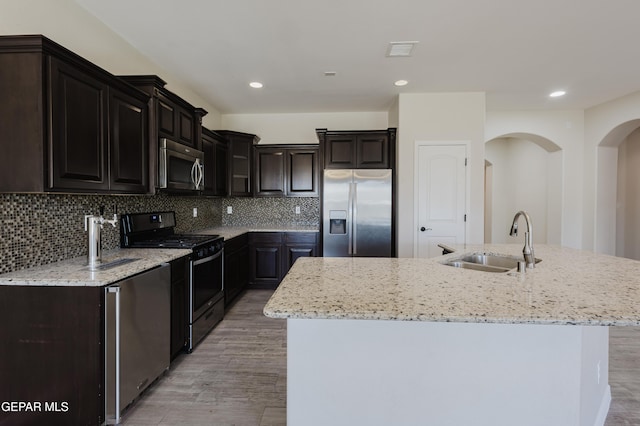 13145 Hazy, El Paso, TX 79938 - kitchen featuring appliances with stainless steel finishes, light wood-style flooring, an island with sink, light stone counters, and backsplash